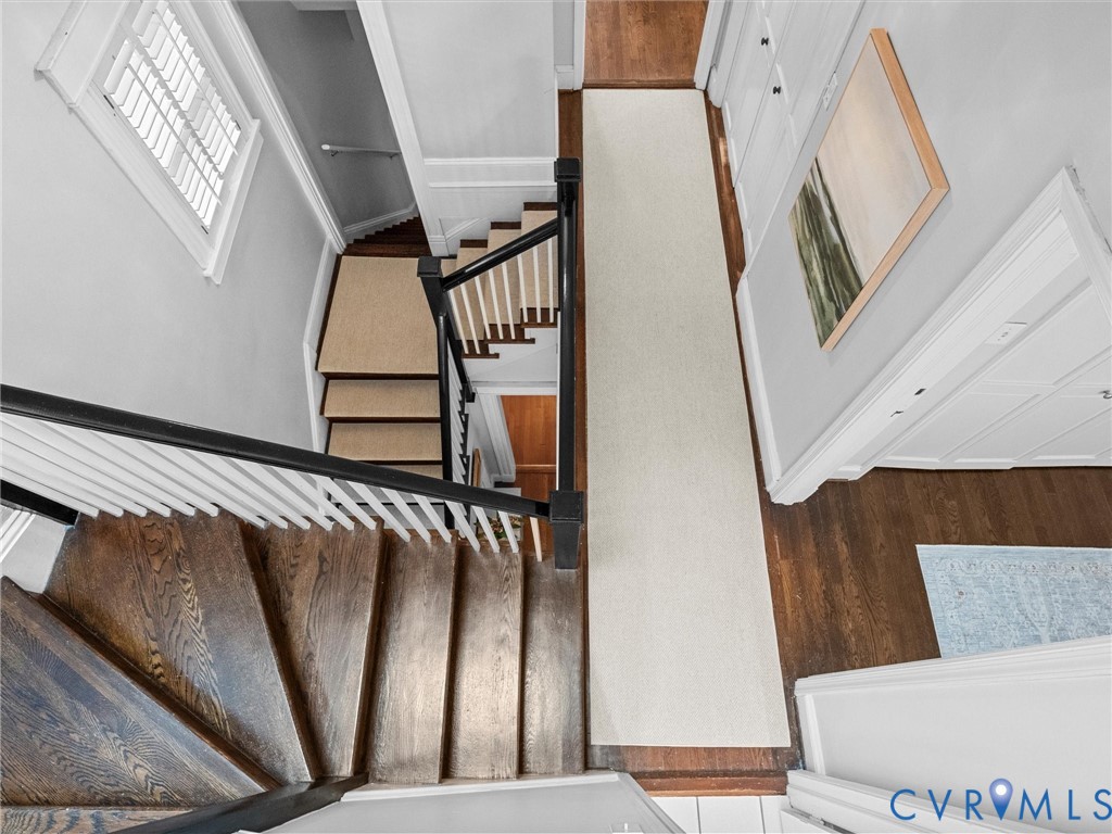 Hardwood staircase with white balusters and a dark handrail