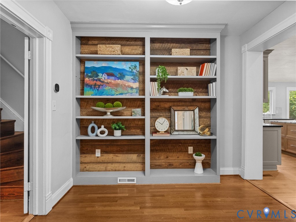 Built-in shelving with reclaimed wood backing, crown molding, and hardwood flooring