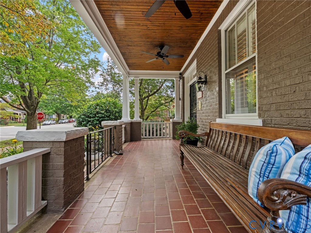 Expansive covered porch featuring a wood-finish ceiling, two ceiling fans, and white architectural columns