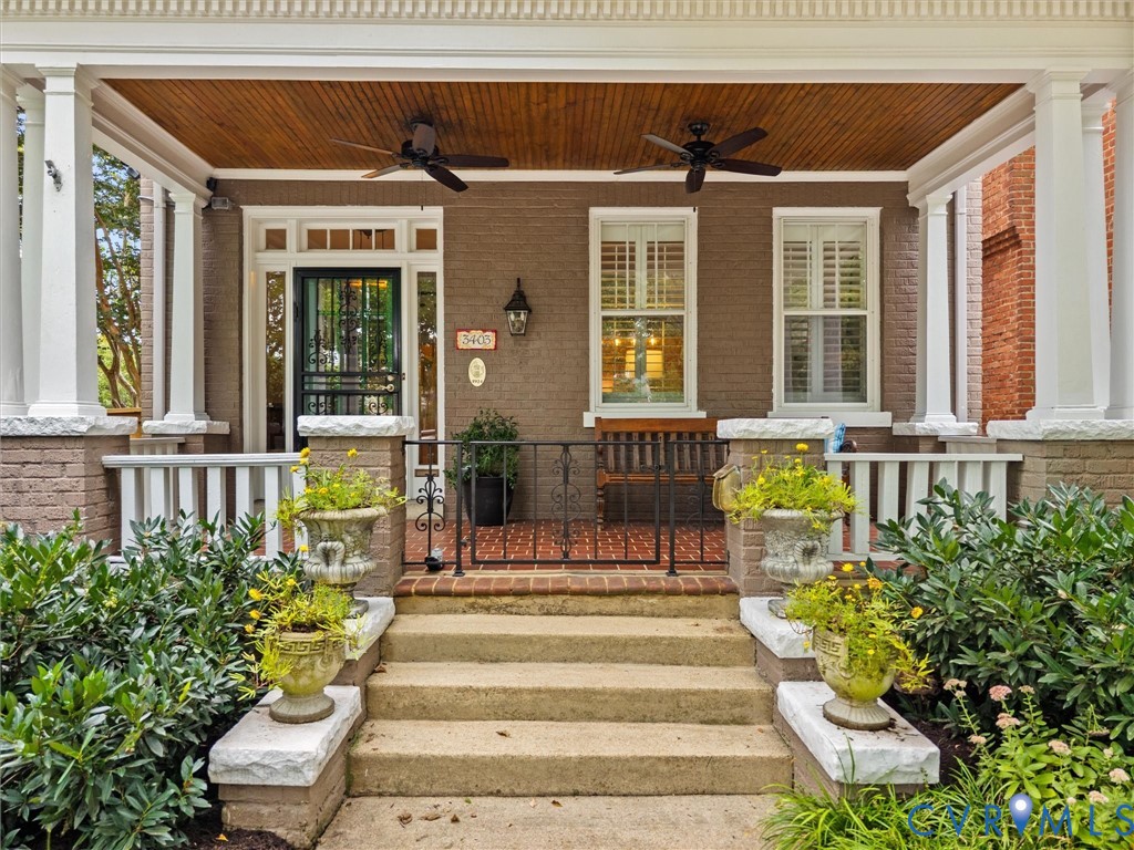 Expansive covered porch featuring a wood-finish ceiling, two ceiling fans, and white architectural columns