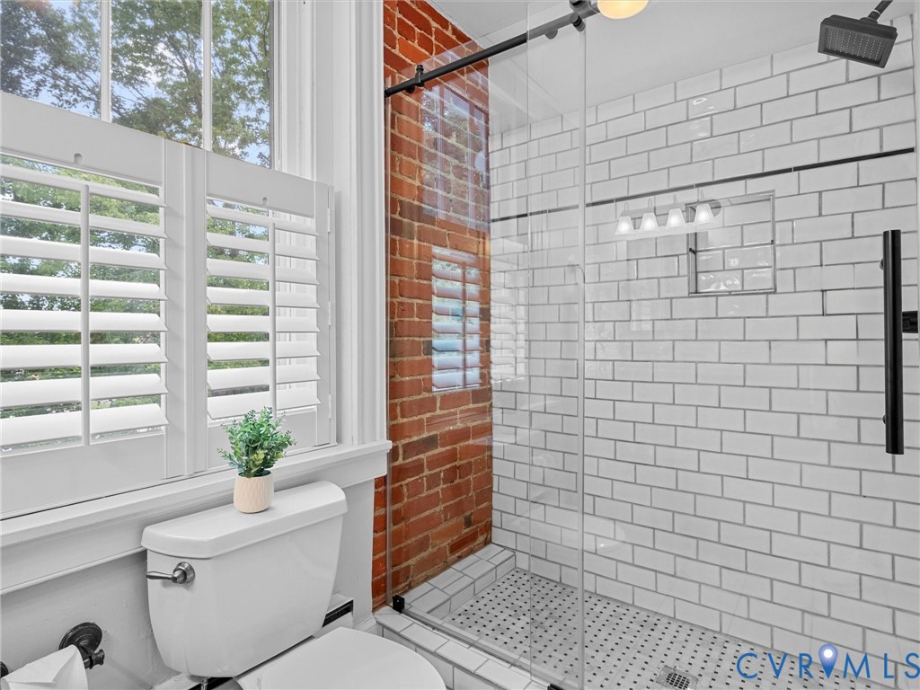 White subway tile shower with a recessed niche, glass enclosure, and matte black fixtures