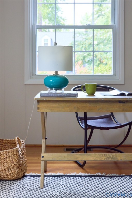 Double-hung window with grid pattern, light-toned wall paint, and wood-finish flooring