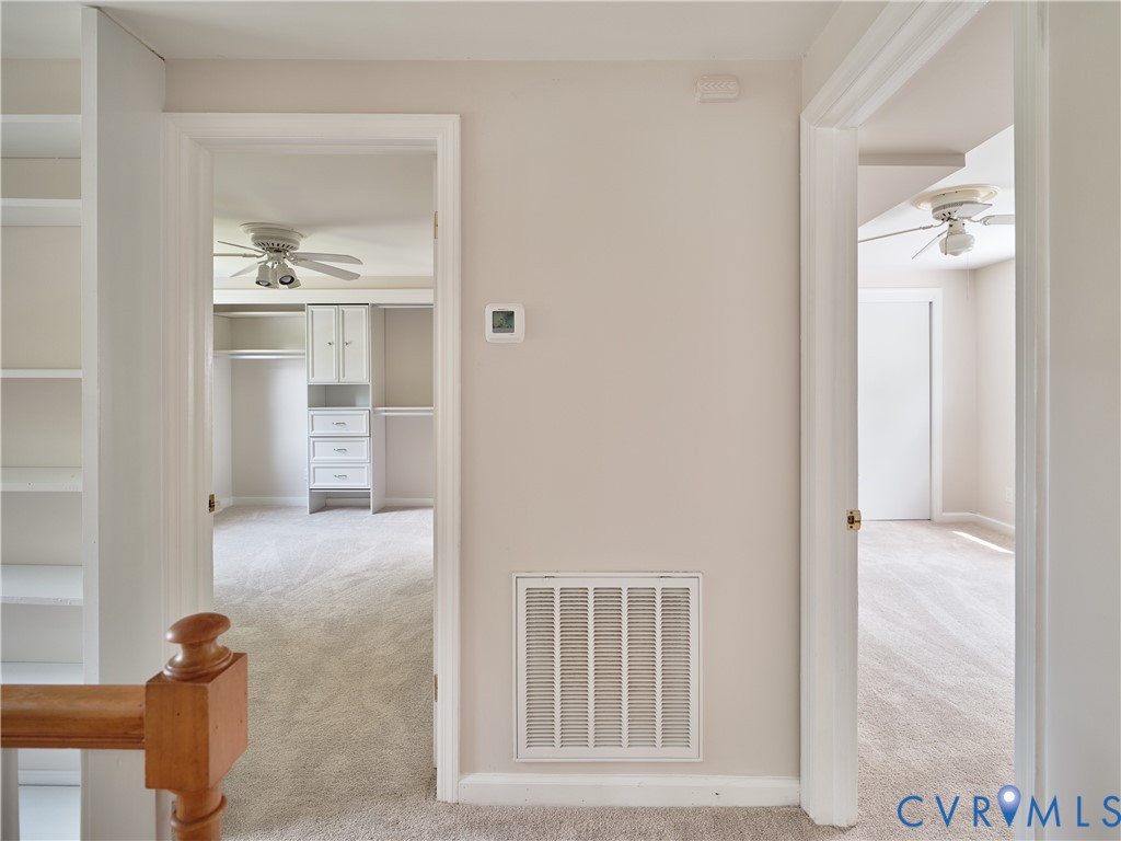 Built-in shelving, wood newel post, neutral wall color, built-in closet organization system, and ceiling fan