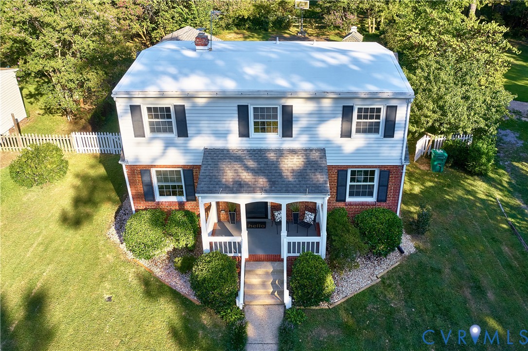 Two-story residence featuring a covered front porch, white siding, and a brick lower exterior