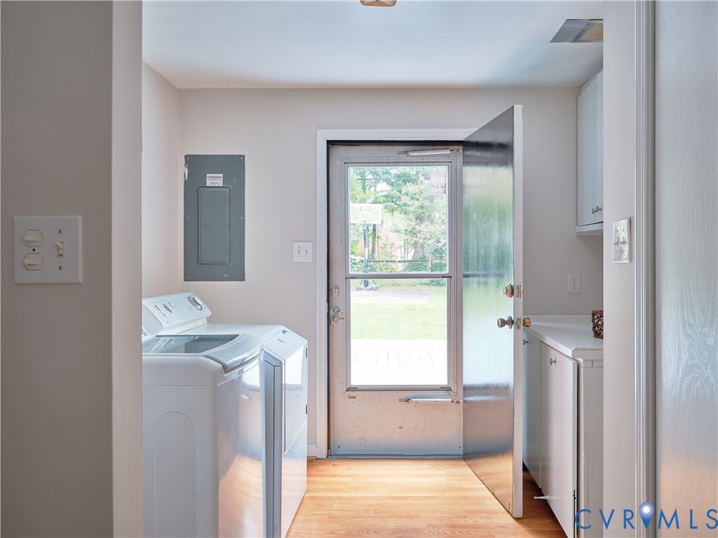 Laundry area with wood-finish flooring, white cabinetry, a built-in countertop, and a rear door with a screen
