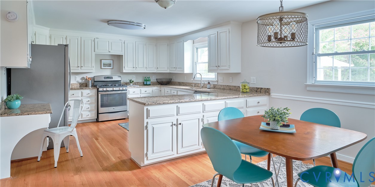 U-shaped kitchen featuring white cabinetry, light-toned countertops, and stainless steel appliances