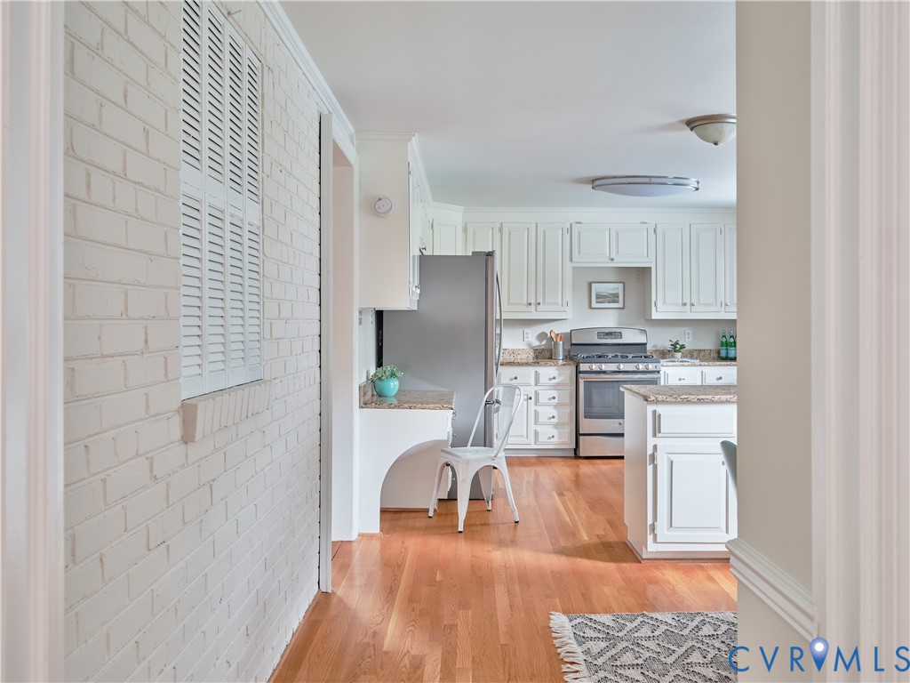 Kitchen featuring white cabinetry, granite countertops, stainless steel appliances, and wood-finish flooring