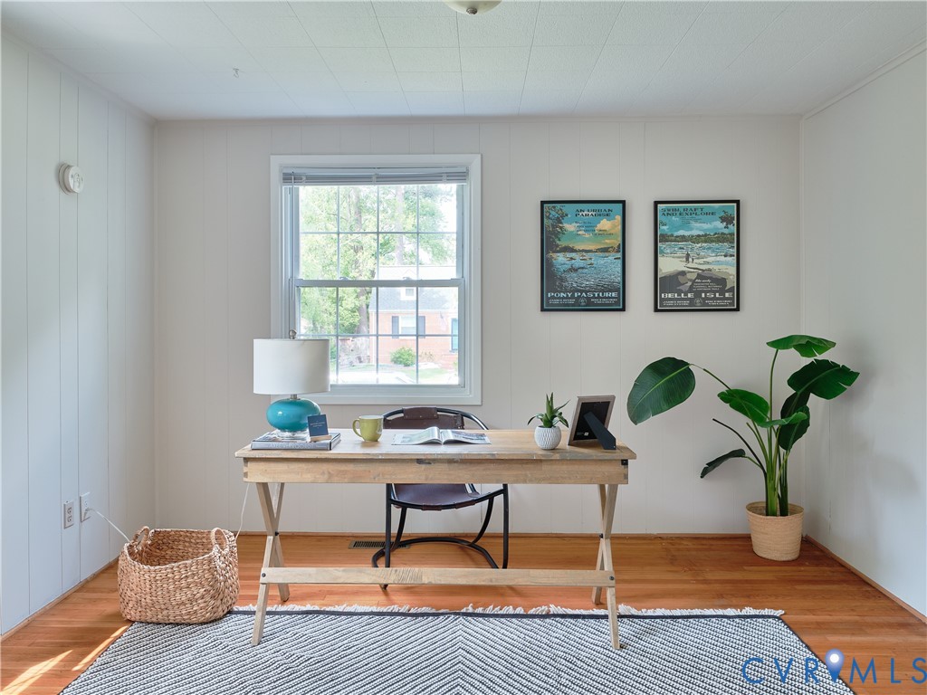 Hardwood flooring, painted paneled wall, double-hung window, and a textured ceiling
