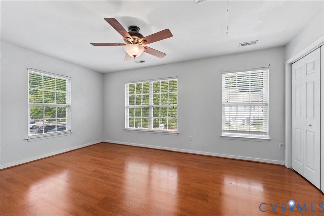Wood-finish flooring with multiple windows and a ceiling fan