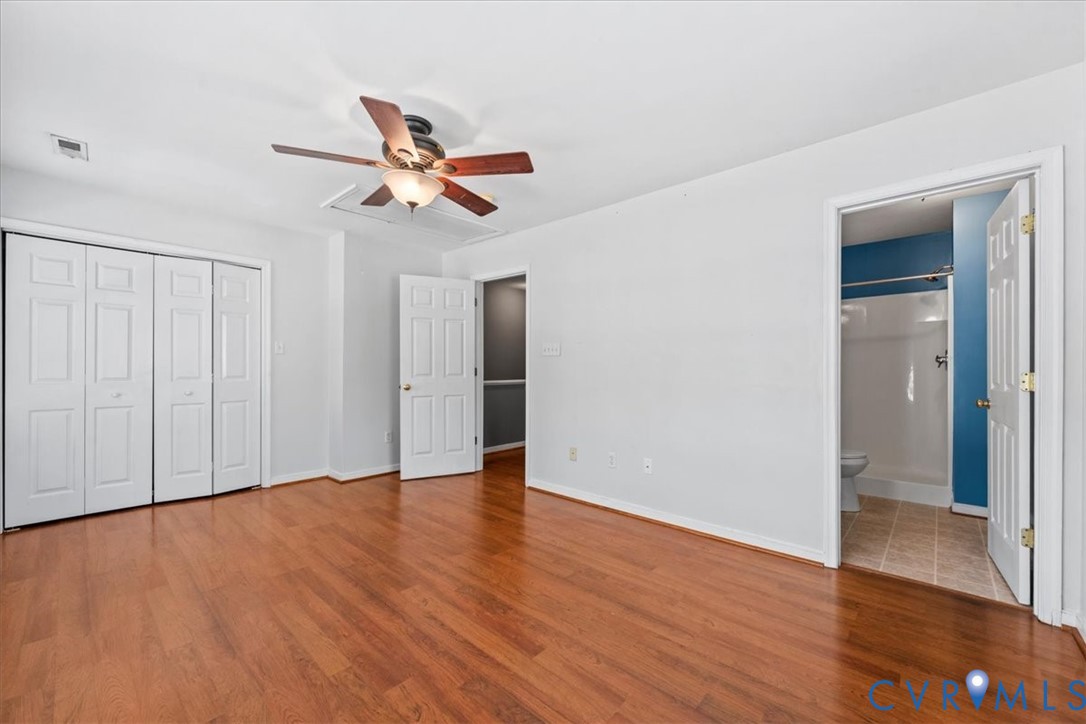 Wood-finish flooring, ceiling fan with integrated lighting, bi-fold closet doors, white paneled interior doors, and a bathroom with a shower-tub combination