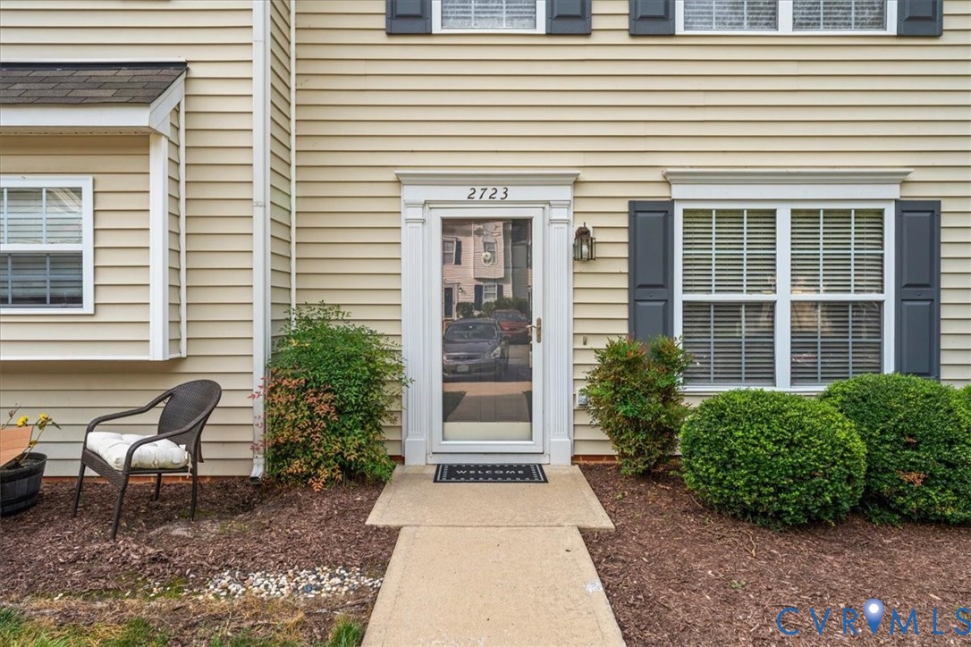 Beige horizontal siding facade with white window trim and dark shutters