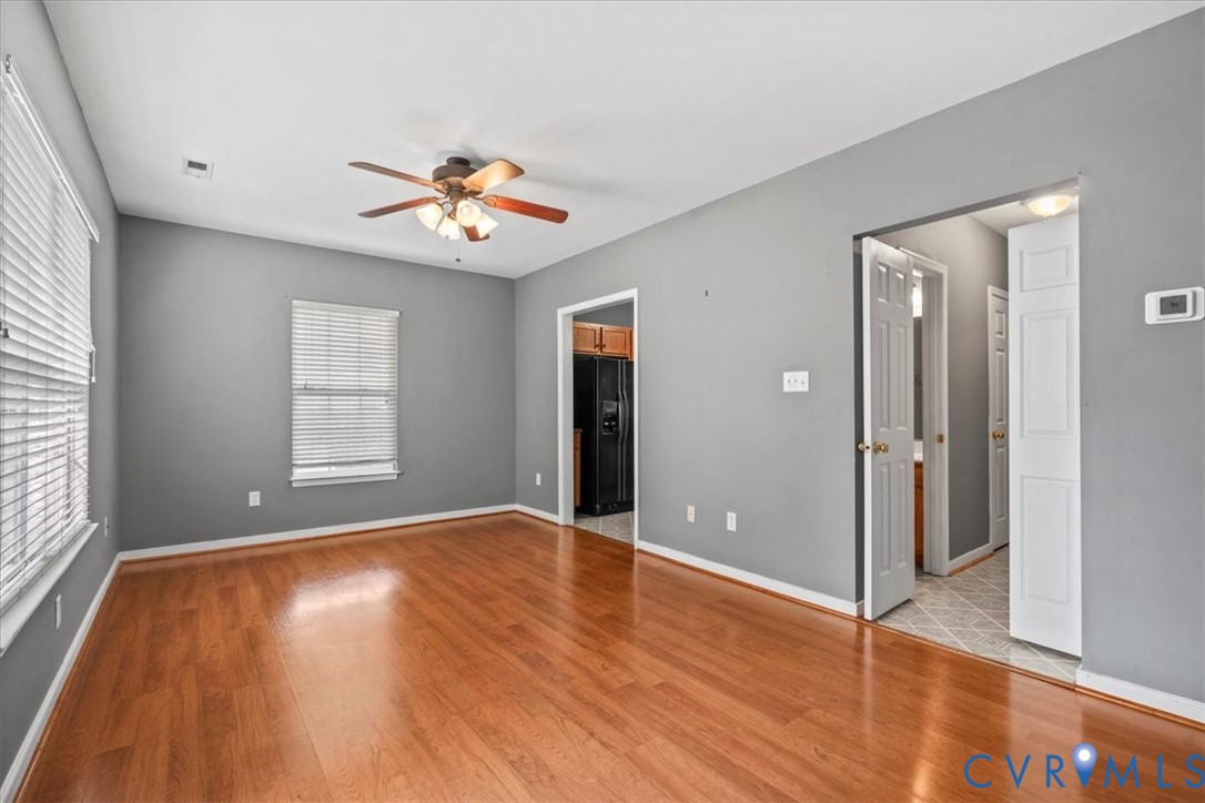 Hardwood-style flooring throughout, ceiling fan with integrated lighting, multiple windows with blinds, and white panel doors