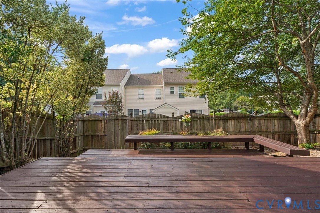 Spacious wood-finish decking with built-in seating, surrounded by mature trees and a wood fence