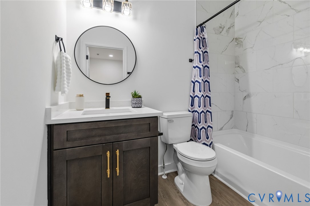 Bathroom featuring a wood-finish vanity with gold-tone hardware, white countertop, and an undermount sink with a matte black faucet