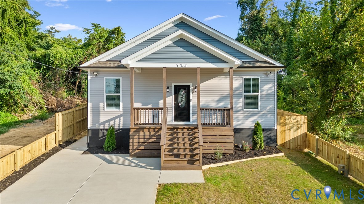 Contemporary exterior featuring light grey siding with blue gables, a covered front porch, and a dark wood-finish railing
