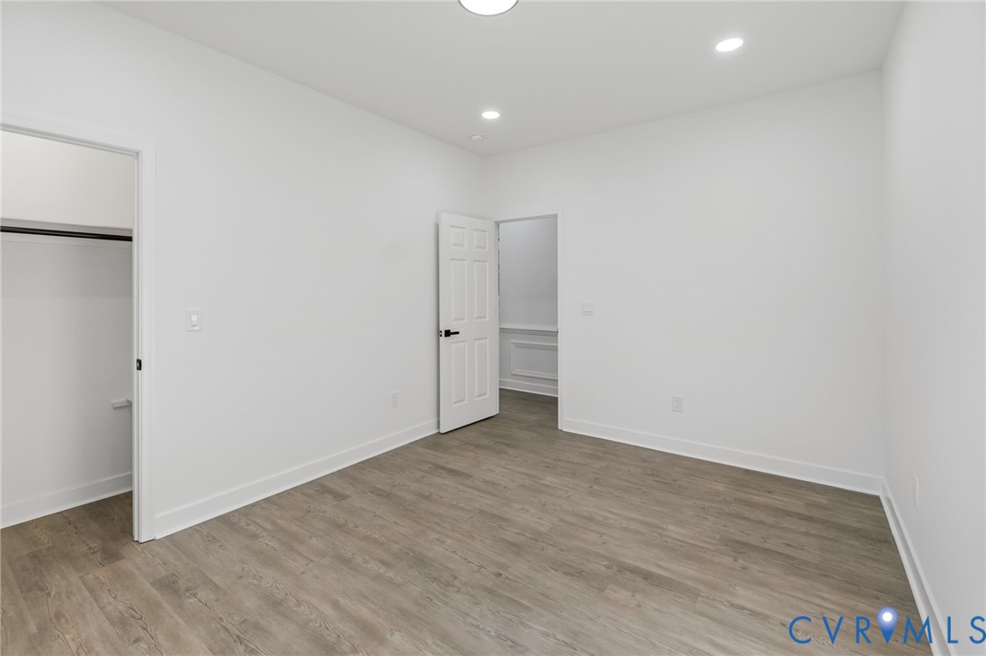 Recessed lighting, wood-finish flooring, white walls, and a closet with hanging rod