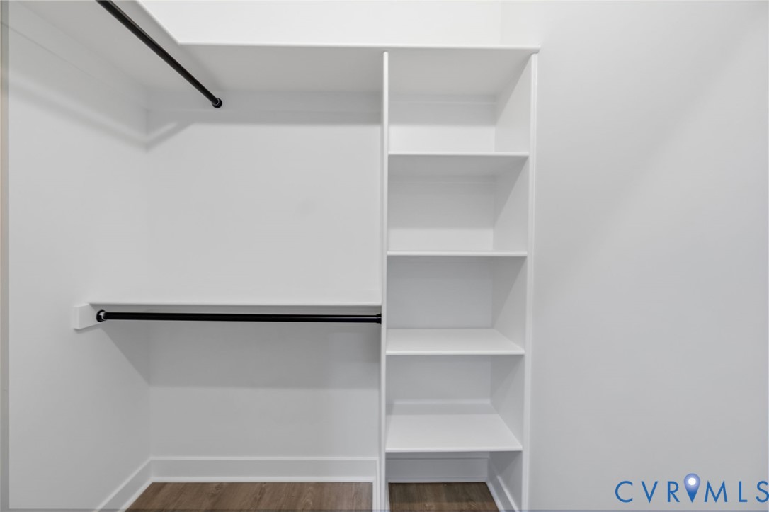 Built-in closet system featuring multiple shelves, two hanging rods, and wood-finish flooring