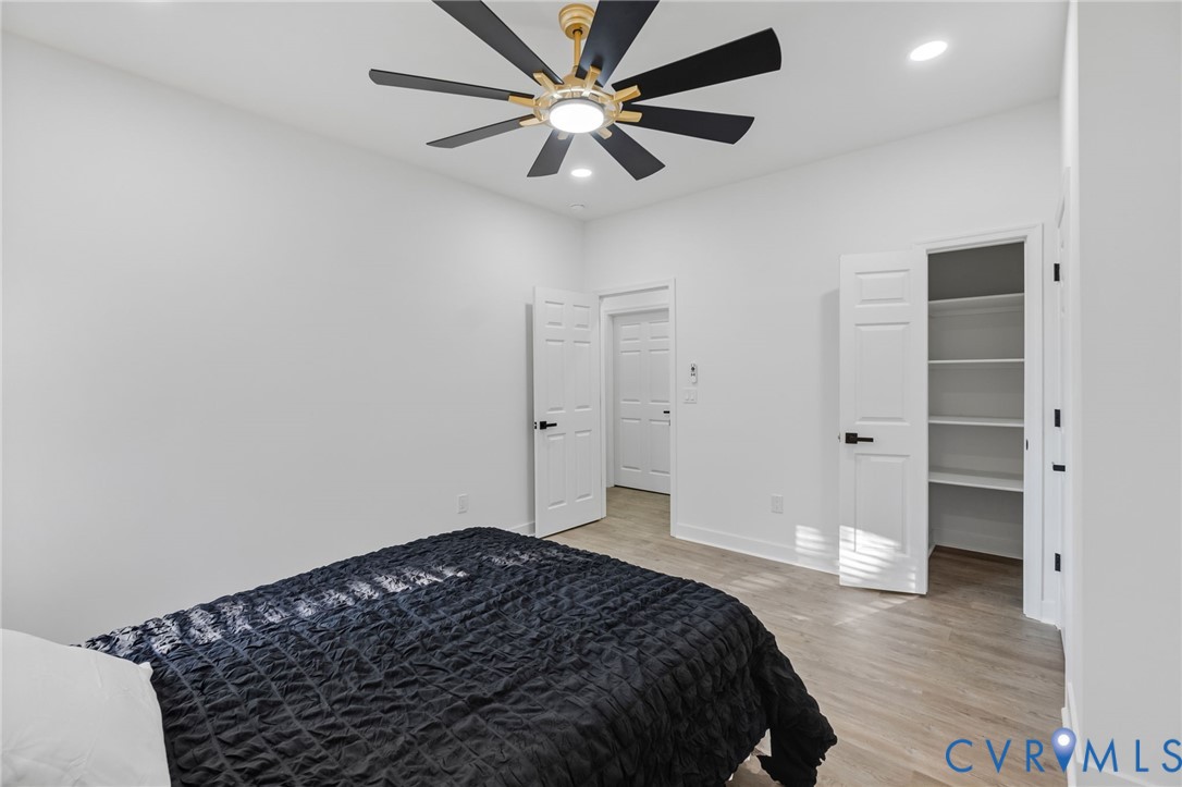 Recessed lighting, wood-finish flooring, ceiling fan with integrated lighting, built-in shelving, and paneled doors