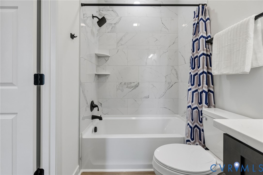 Bathtub with white subway tile surround, matte black fixtures, and built-in shelving