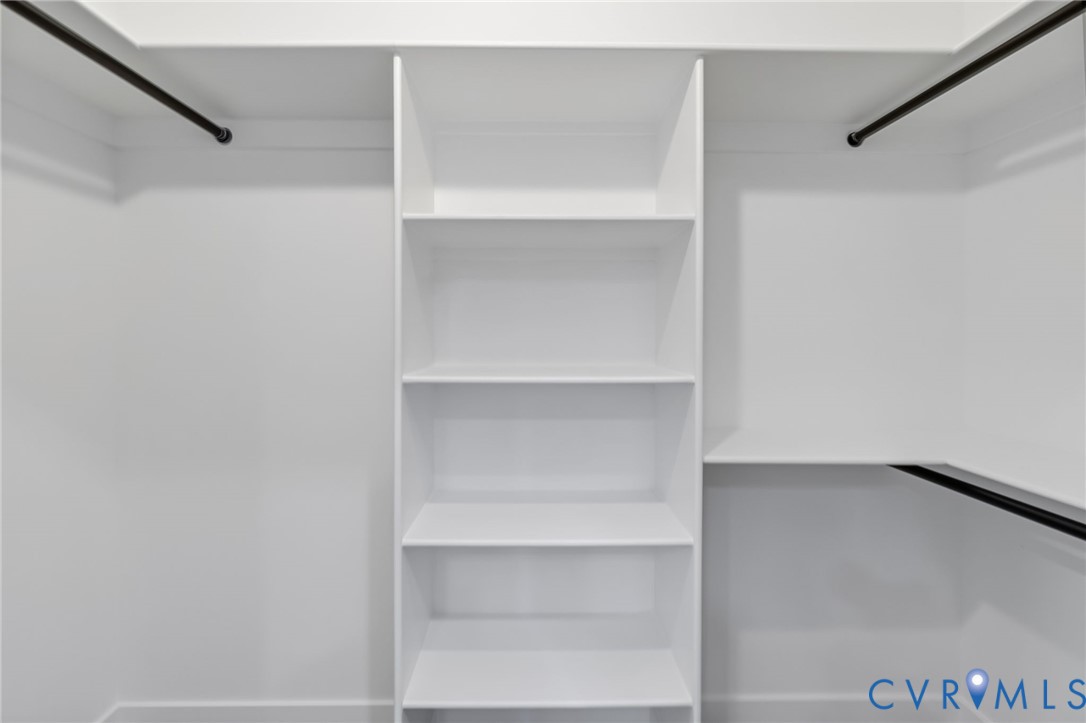 Built-in white shelving, multiple clothing rods, and white painted walls