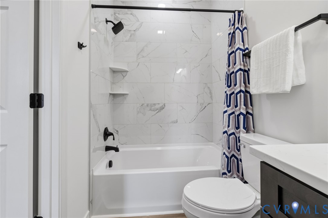 White bathtub with a matte black showerhead and faucet, set against a tiled wall with a marble-like pattern