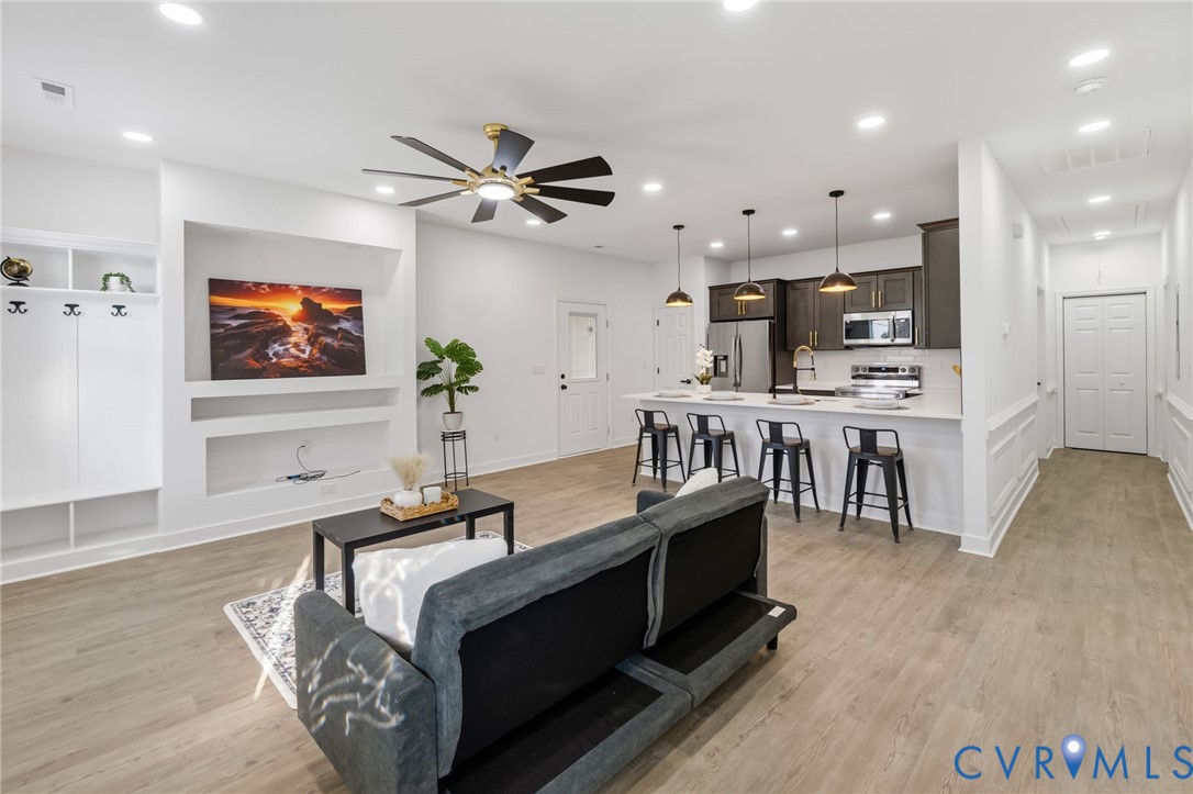 Open-concept living space featuring wood-finish flooring, recessed lighting, and a ceiling fan