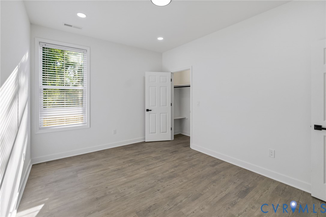 Recessed lighting, wood-finish flooring, and white walls