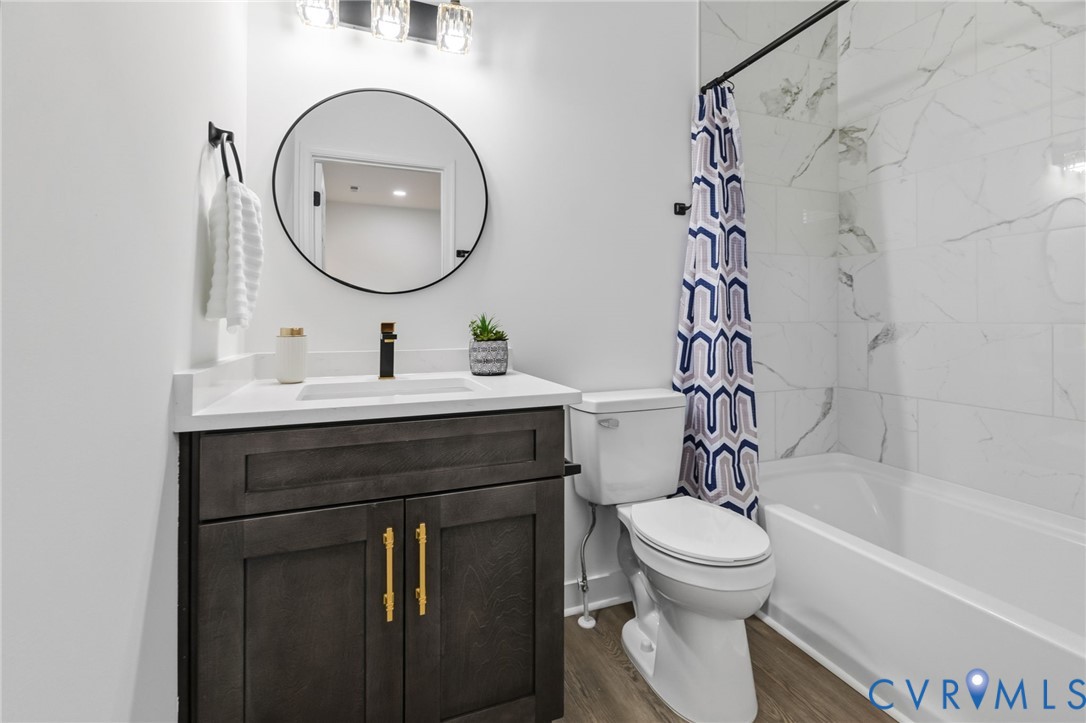 White vanity countertop with an integrated sink, dark wood-finish cabinetry, and gold-tone hardware