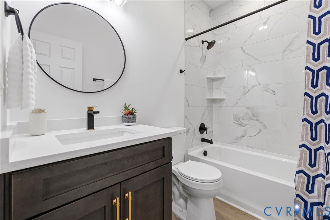 Dark wood-finish vanity with gold-tone hardware, rectangular undermount sink, and a black-and-gold finish faucet