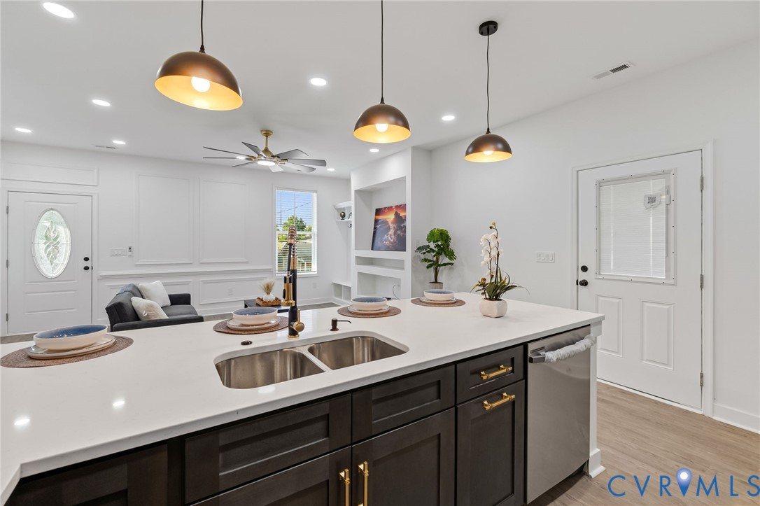 Kitchen island with an undermount double-basin sink, dark wood-finish cabinetry, and a light-toned countertop