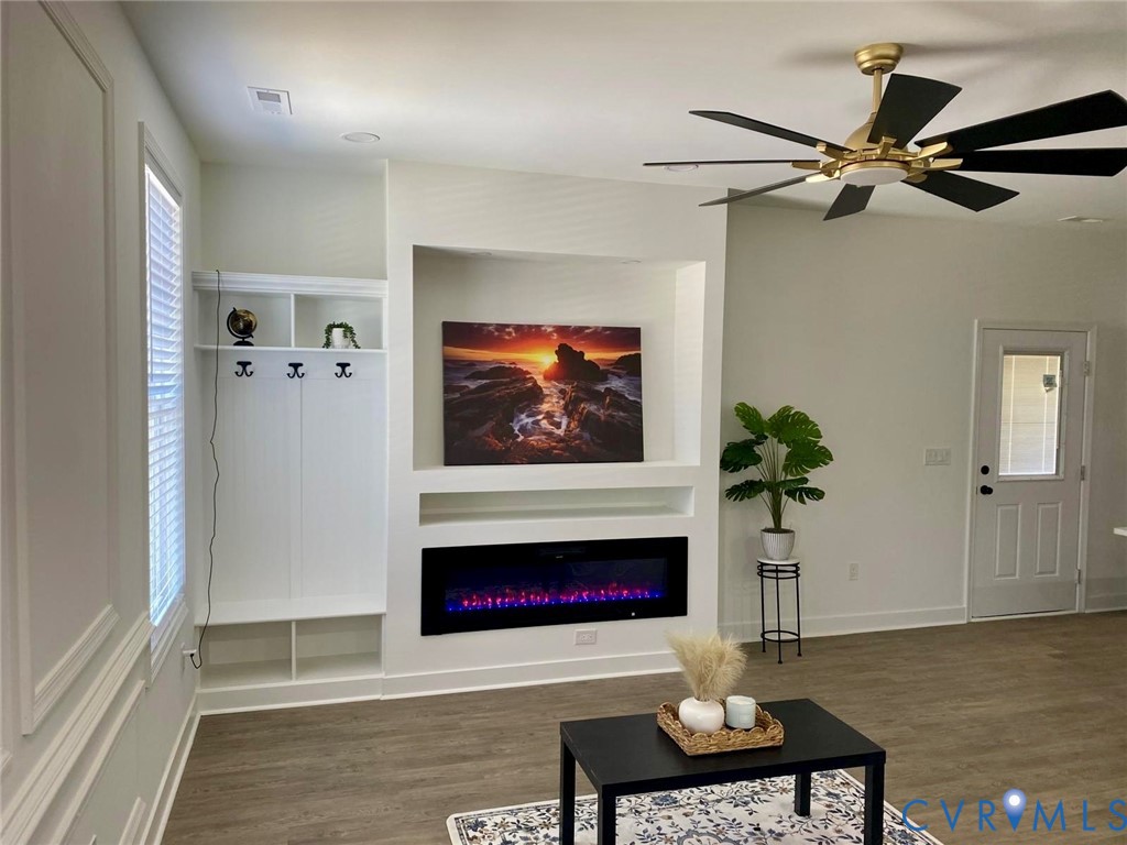 Built-in storage with coat hooks, integrated electric fireplace, contemporary ceiling fan, and wood-finish flooring