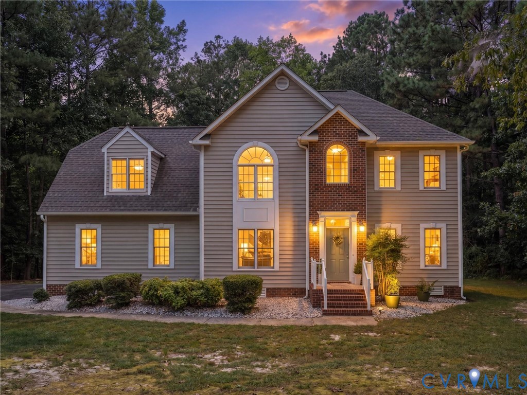 Two-story residence featuring siding and brick accents, an arched window, dormer window, and a prominent front entrance with steps Two-story residence featuring siding and brick accents, an arched window, dormer window, and a prominent front entrance with steps