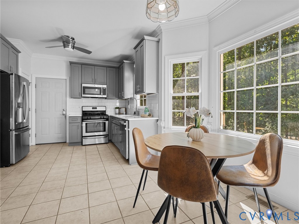 Kitchen featuring gray cabinetry, stainless steel appliances, tile flooring, and a large bay window