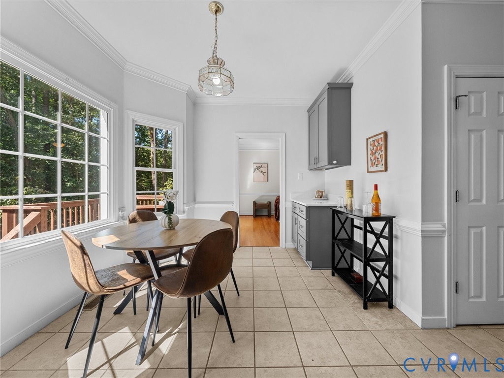 Bay window with grid pattern, tiled flooring, built-in cabinetry with white countertop, crown molding, and recessed lighting