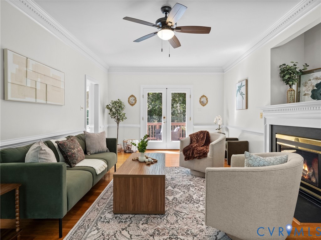 Hardwood flooring, crown molding, built-in fireplace, ceiling fan with lighting, and French doors leading to exterior space Hardwood flooring, crown molding, built-in fireplace, ceiling fan with lighting, and French doors leading to exterior space