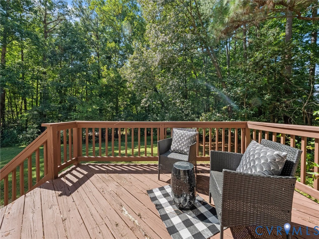 Wood-finish deck with a built-in railing overlooking a dense tree line