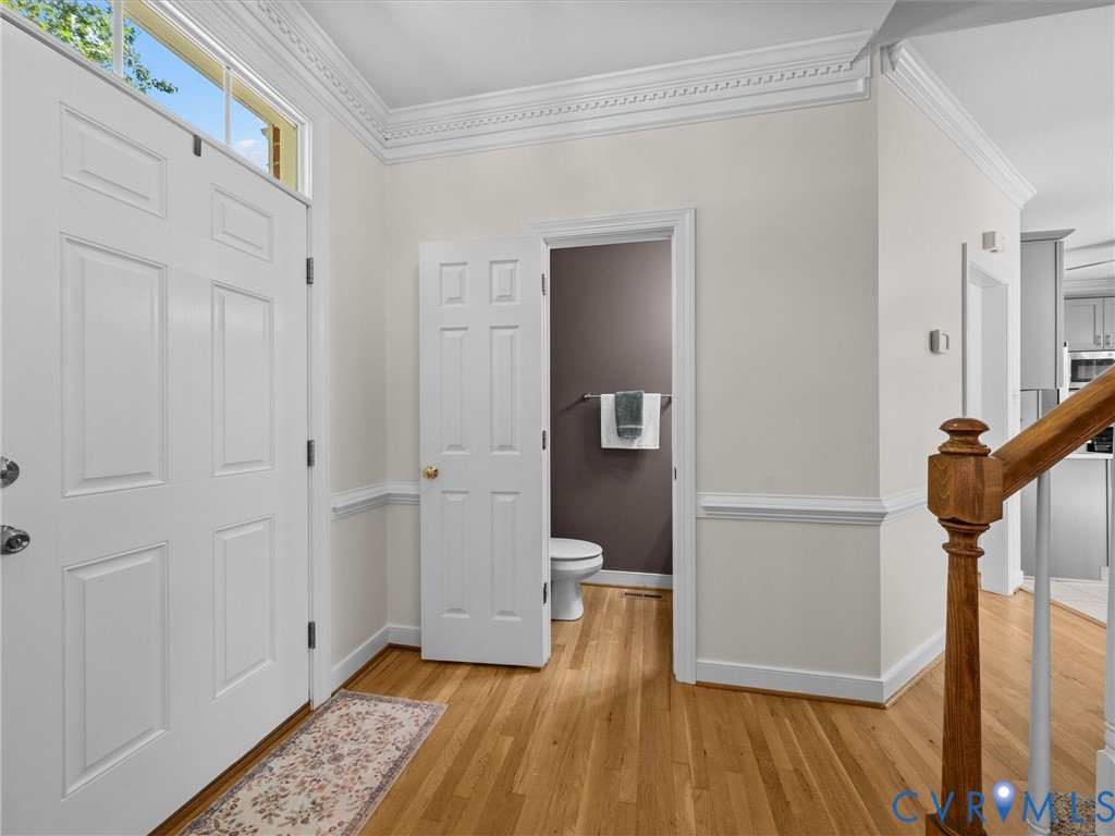 Hardwood flooring, decorative crown molding, wainscoting, solid paneled interior door, and a wooden stair railing Hardwood flooring, decorative crown molding, wainscoting, solid paneled interior door, and a wooden stair railing