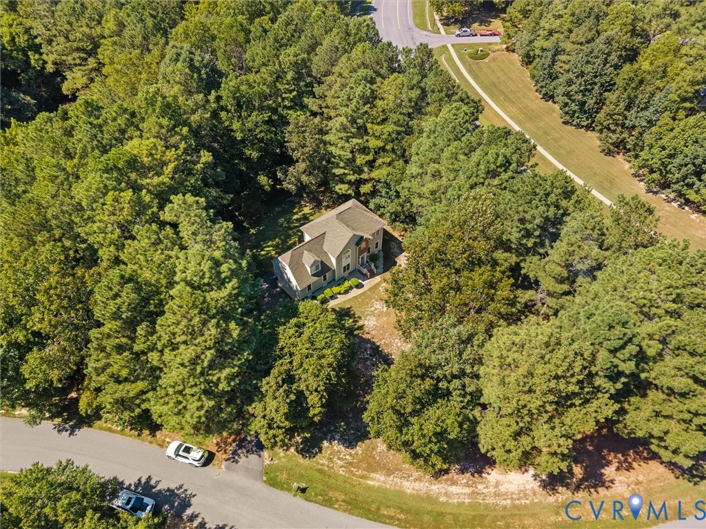 Tree-lined property with a multi-story residence featuring a gabled roof and surrounding natural landscape