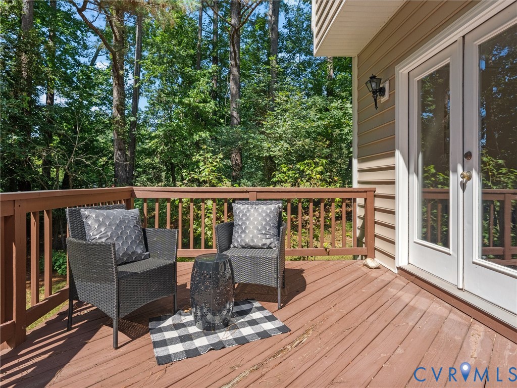 Expansive wood deck with wood railings, double glass-paneled doors, and exterior wall siding