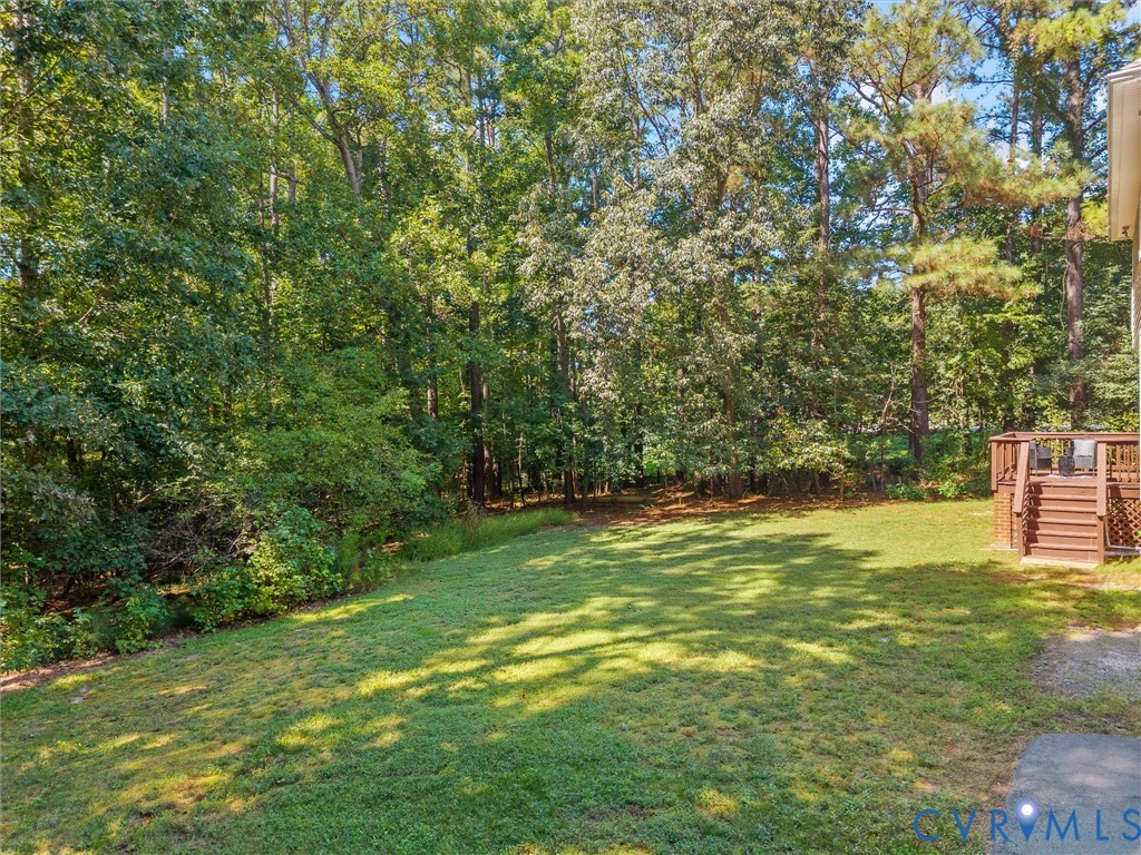 Expansive backyard with a manicured lawn, established trees, and a multi-level wood deck
