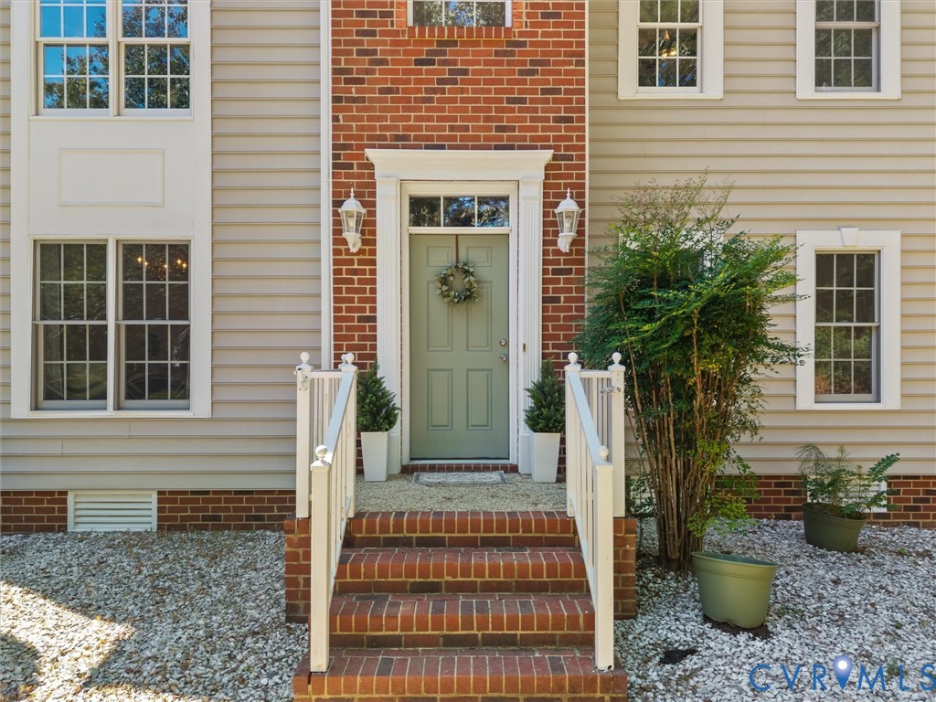 Brick and siding exterior with a light green entry door, white trim, and white handrails