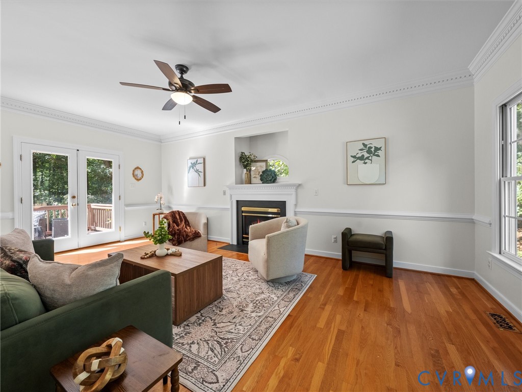 Hardwood flooring, crown molding, chair rail molding, built-in fireplace, and double French doors with transom windows
