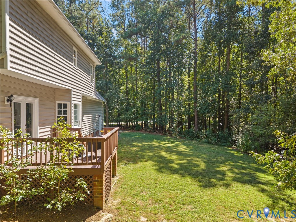 Spacious backyard with a wooden deck, mature trees, and a manicured lawn