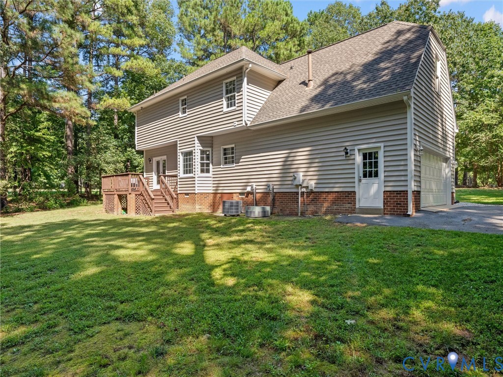 Wooded lot with a multi-level deck, two-car garage, and a side entrance door