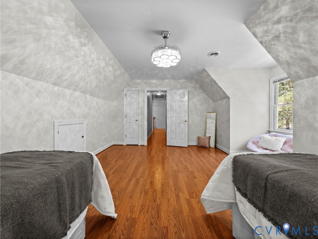Hardwood flooring, sloped ceilings, ceiling-mounted light fixture, dual pane window, and multiple panel doors
