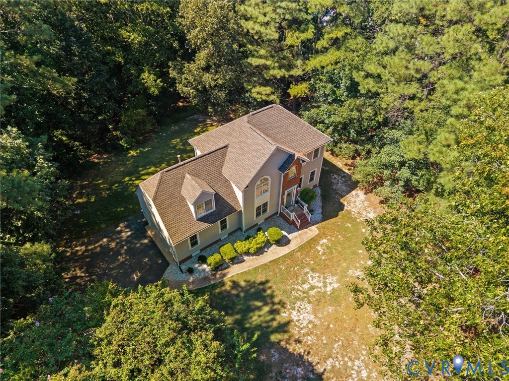Two-story residence with a dormer, arched window, and landscaped front entry
