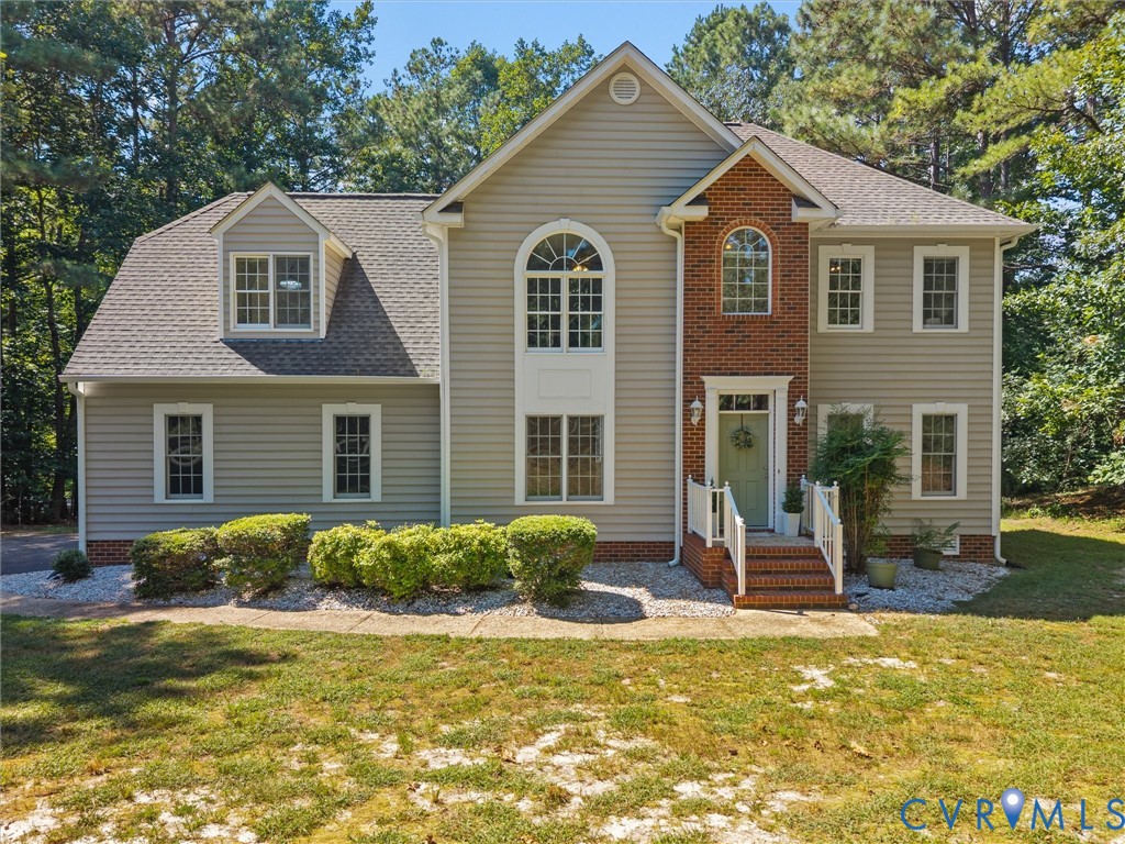 Two-story residence featuring light-colored siding, brick accents, white trim, and a prominent arched window above the entry Two-story residence featuring light-colored siding, brick accents, white trim, and a prominent arched window above the entry
