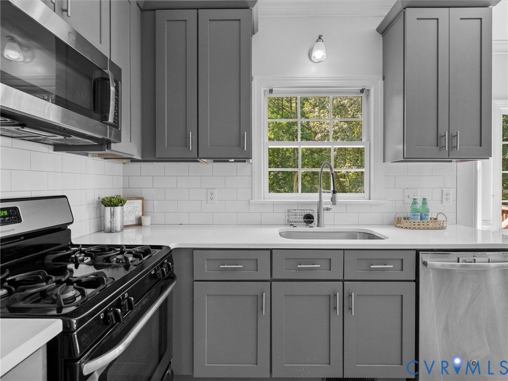 Kitchen featuring gray shaker-style cabinetry, stainless steel appliances, a subway tile backsplash, white countertops, and a stainless steel sink with a gooseneck faucet