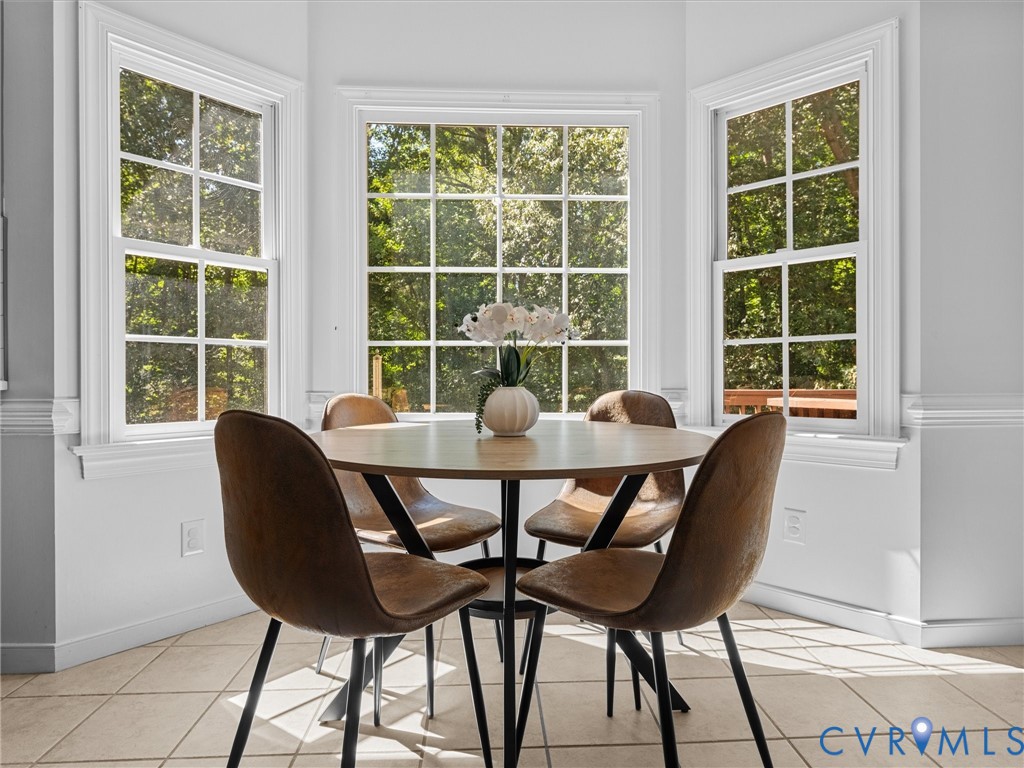 Bay window with multiple pane windows, crown molding, chair rail molding, and tile flooring