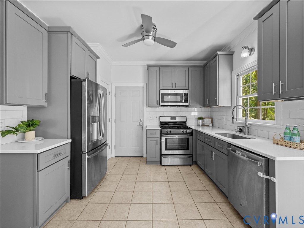 Kitchen featuring gray cabinetry, stainless steel appliances, a subway tile backsplash, white countertops, and tile flooring Kitchen featuring gray cabinetry, stainless steel appliances, a subway tile backsplash, white countertops, and tile flooring